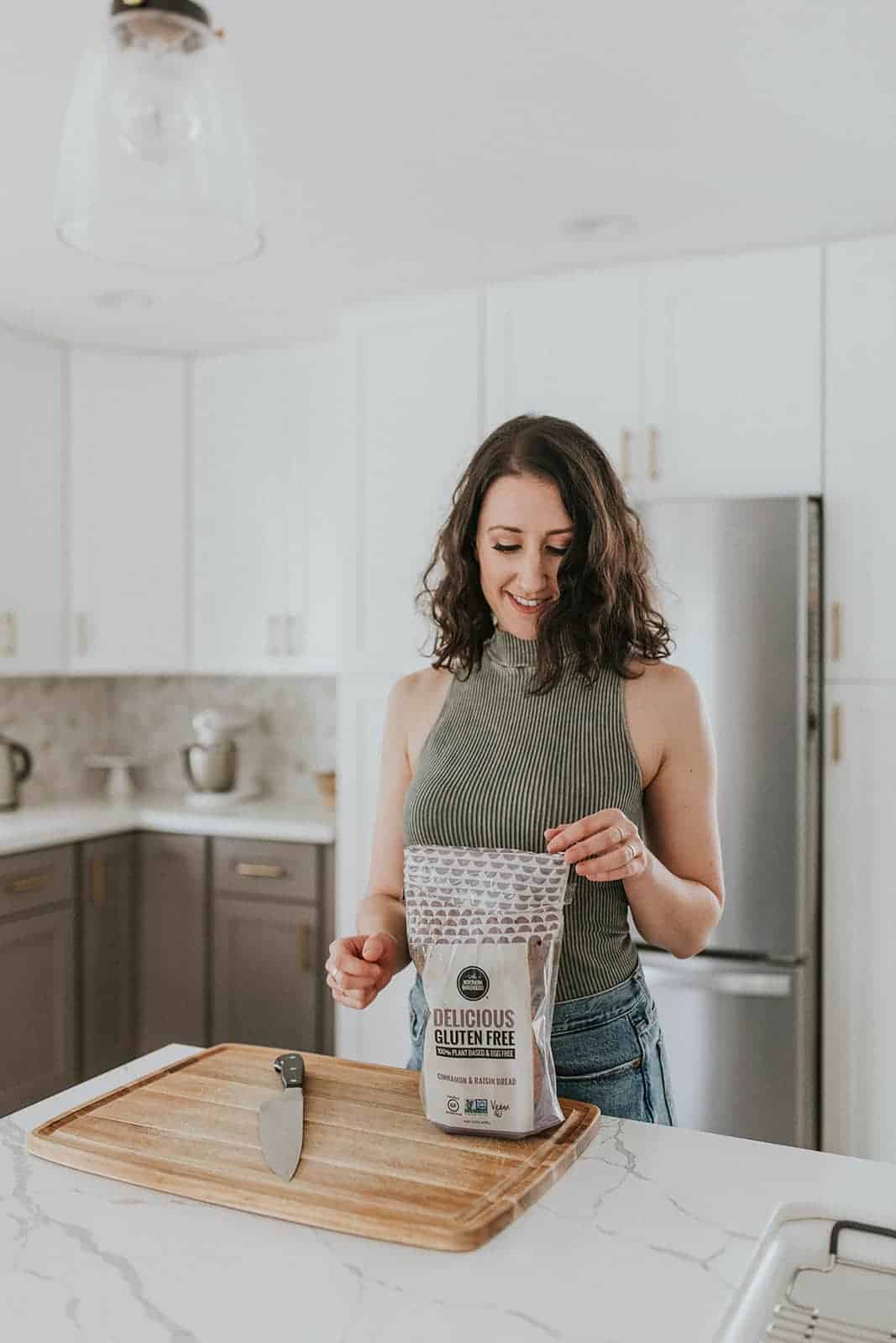 Woman in a kitchen opening a gluten-free pack of bread 