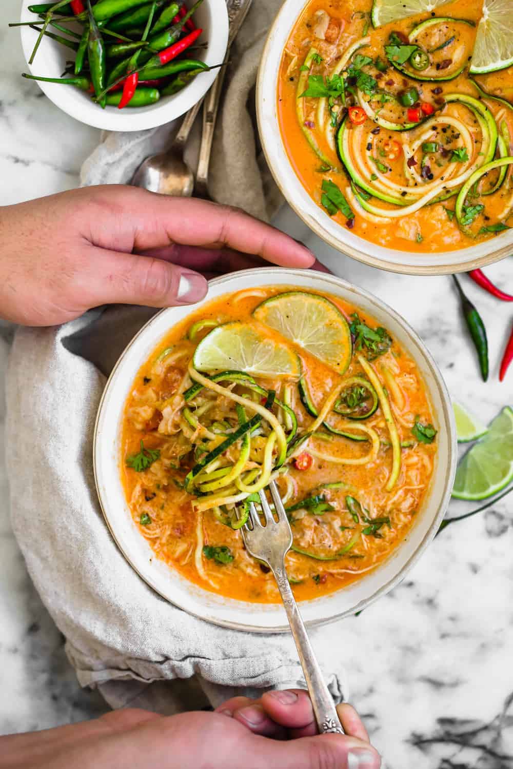 chicken zucchini noodle soup in a bowl being eaten