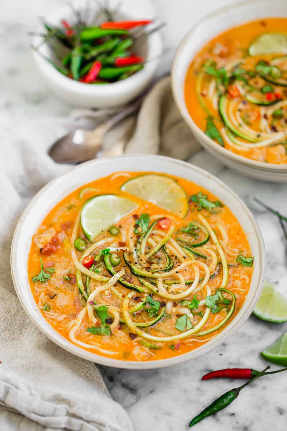 chicken zucchini noodle soup in a white bowl with Thai spices