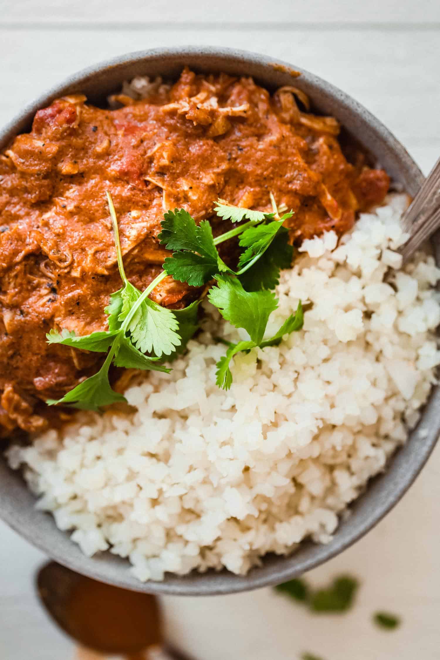 chicken tikka masala in a bowl with flat parsley and rice