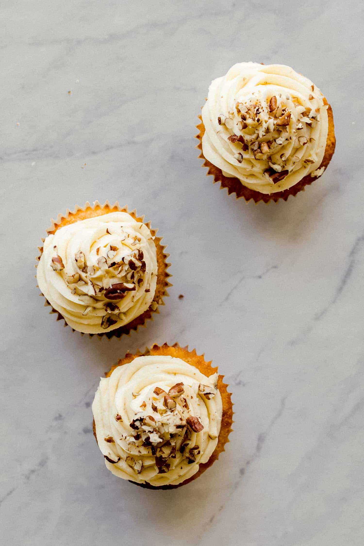 three carrot cake cupcakes with cream cheese frosting