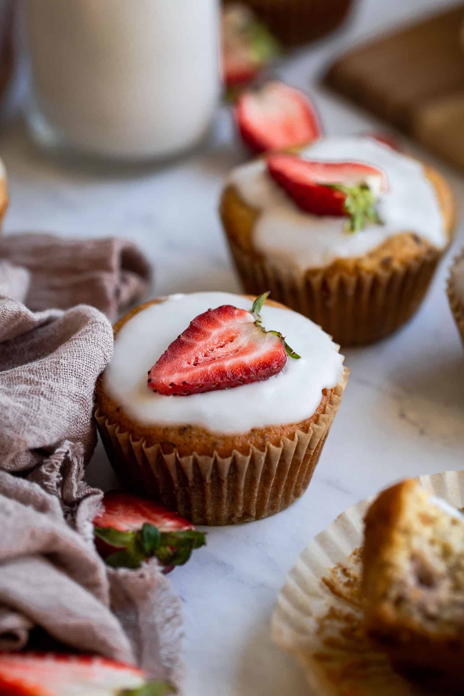 side profile of a muffin with coconut butter glaze and a strawberry on top