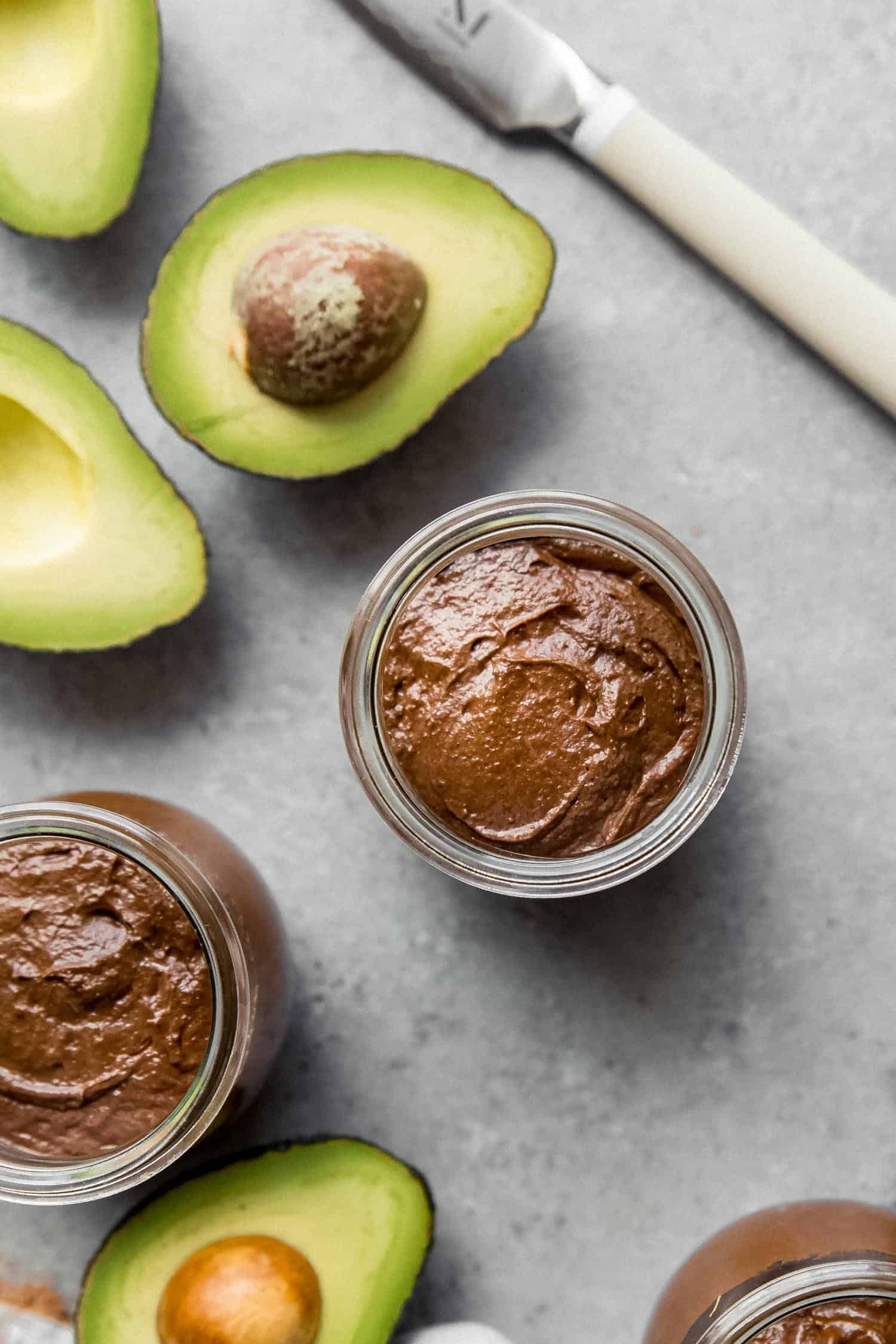 creamy chocolate pudding in glass jars with avocados
