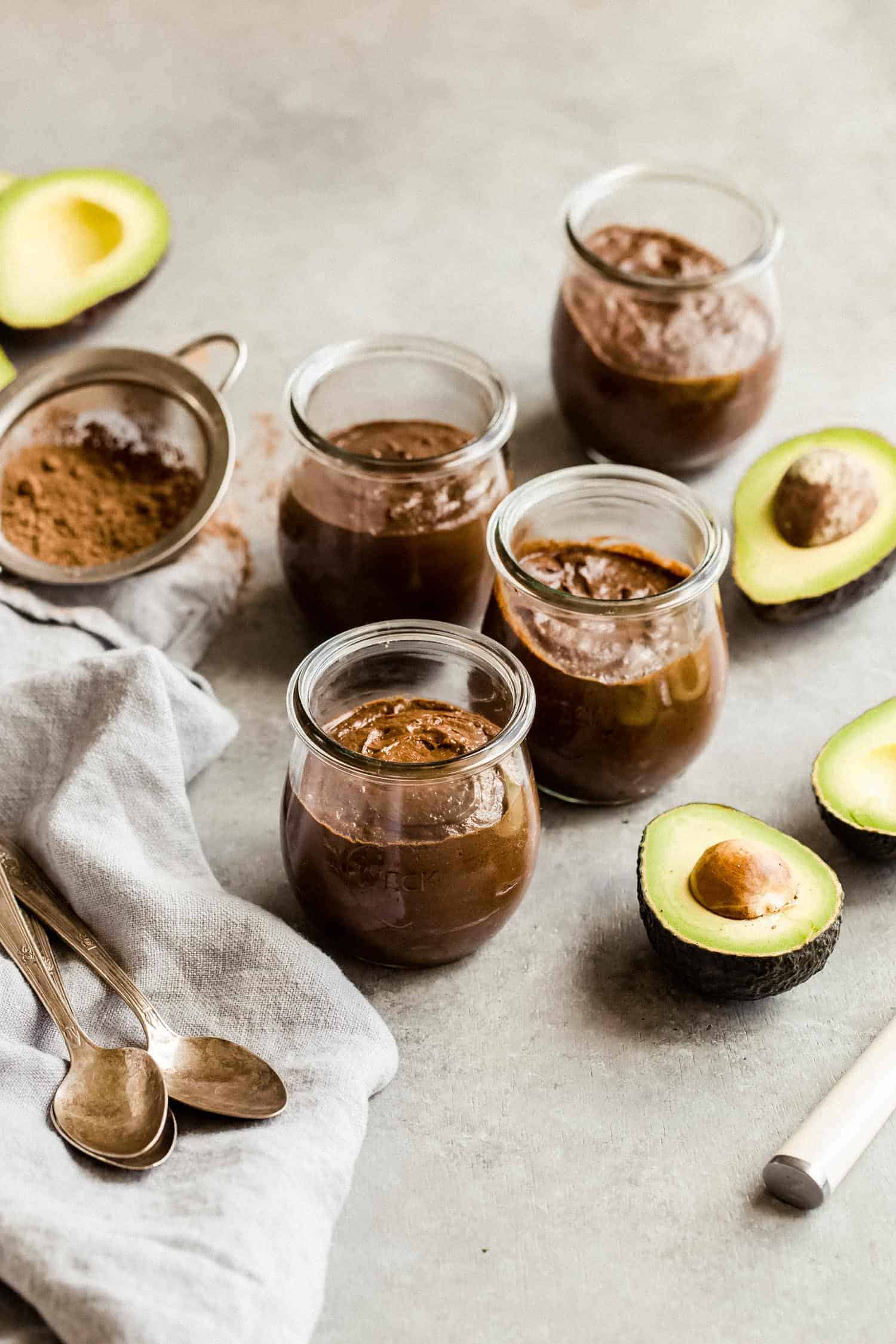 four jars of chocolate pudding with avocado halves