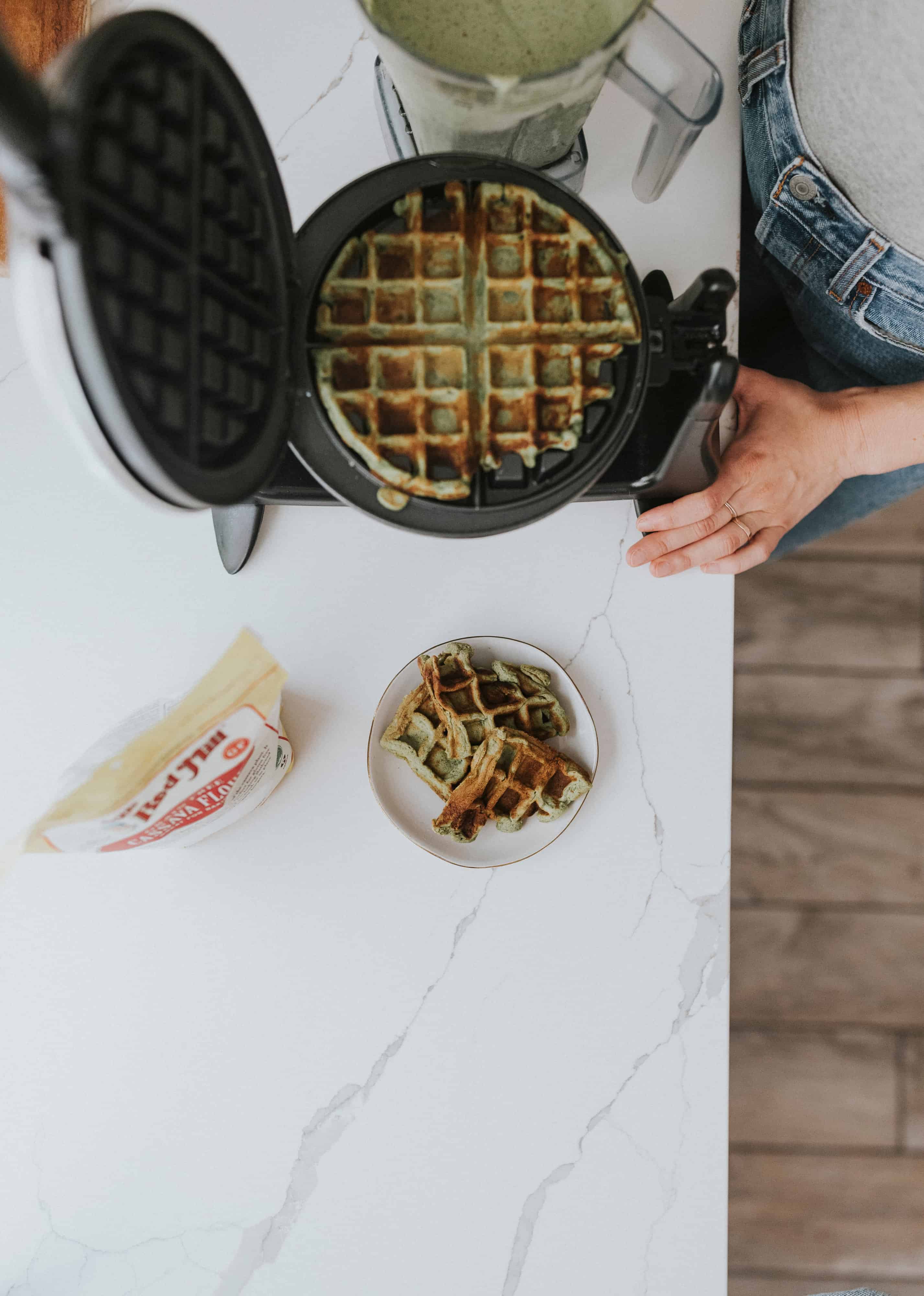 overhead of spinach waffles cooking in a waffle iron