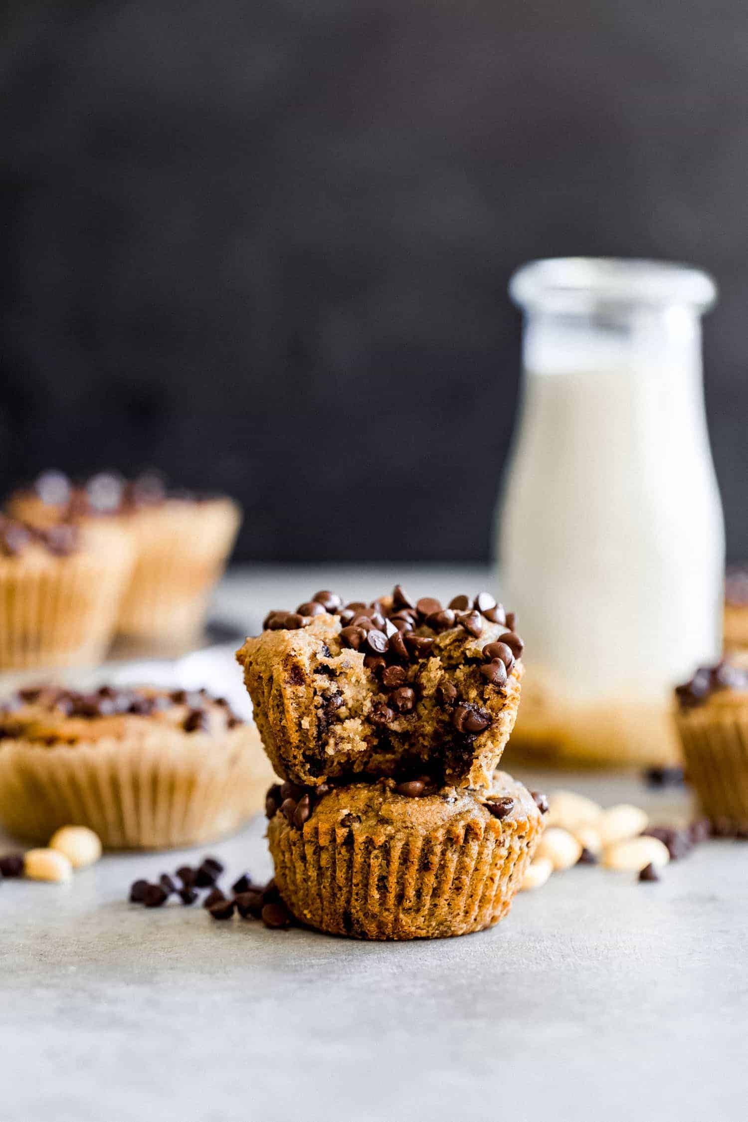 peanut butter banana muffins with dark chocolate chips stacked with a milk jug in the background