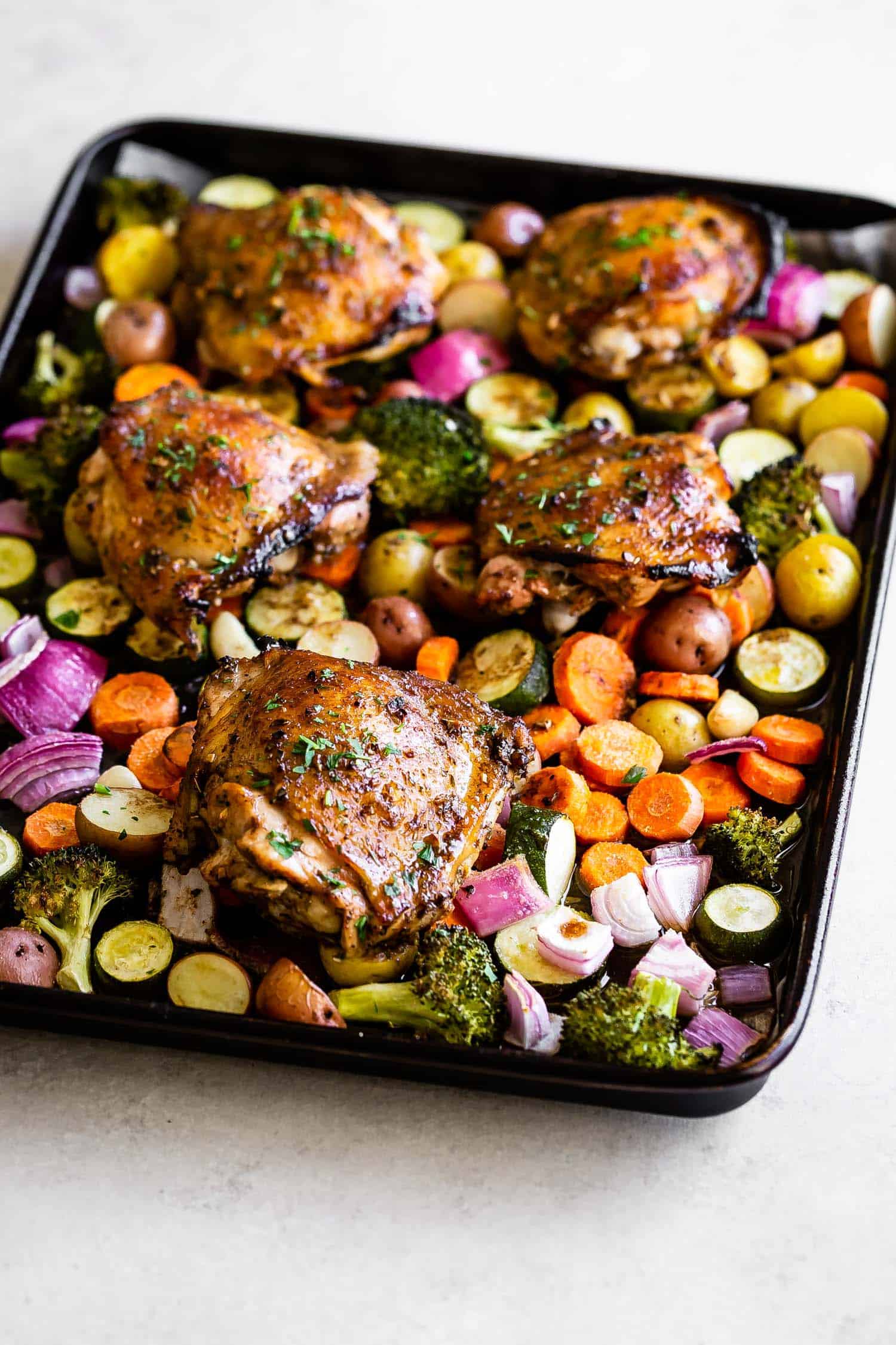 chicken thighs with roasted veggies on a large sheet pan