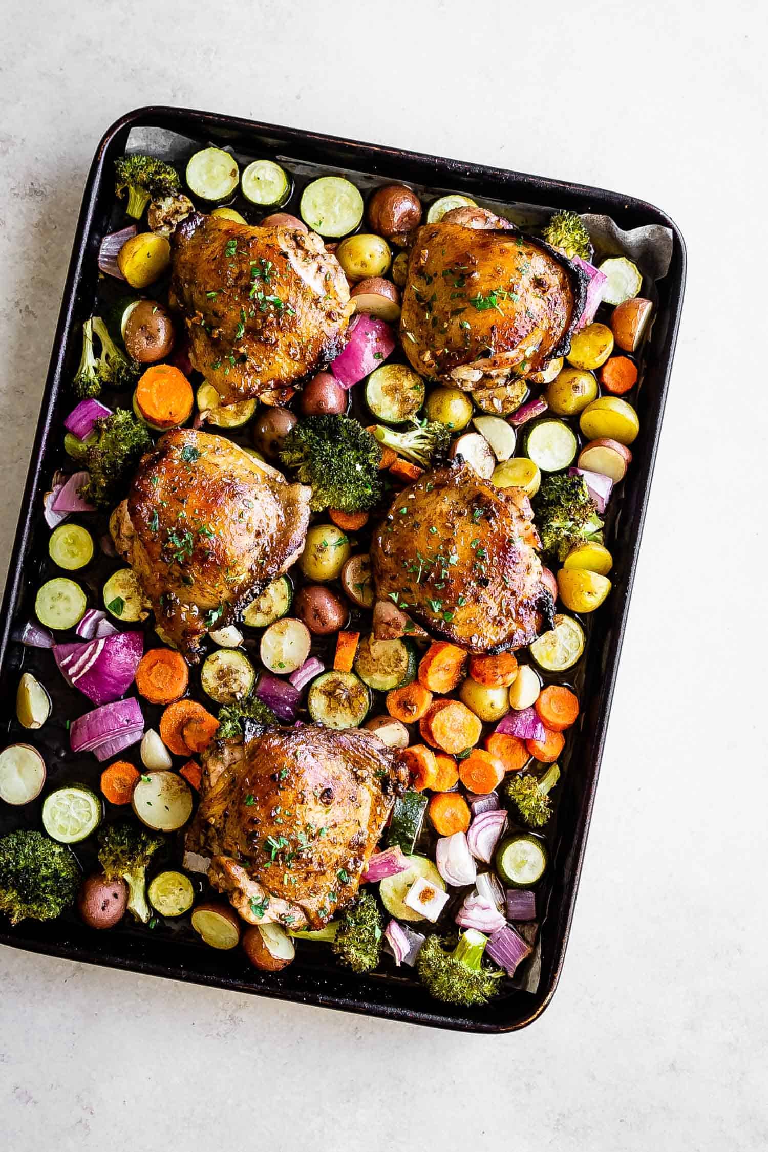 sheet pan full of roasted veggies and crispy chicken thighs