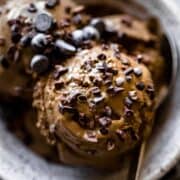 chocolate ice cream scoops in a bowl with cacao nibs and dark chocolate chips