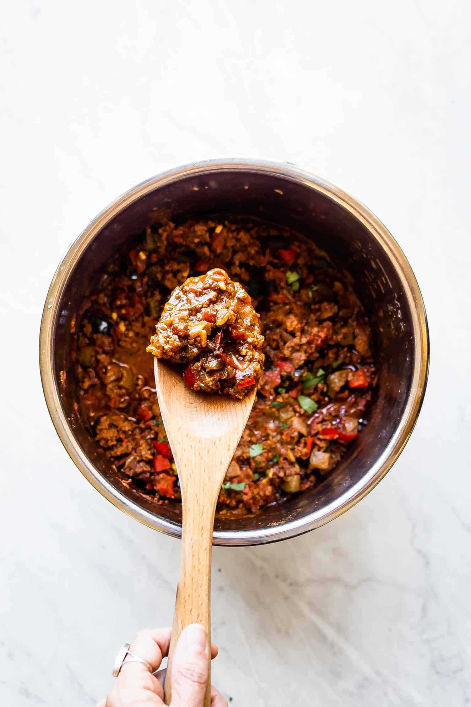 Whole30 chili inside the instant pot with a wooden spoon full of chili