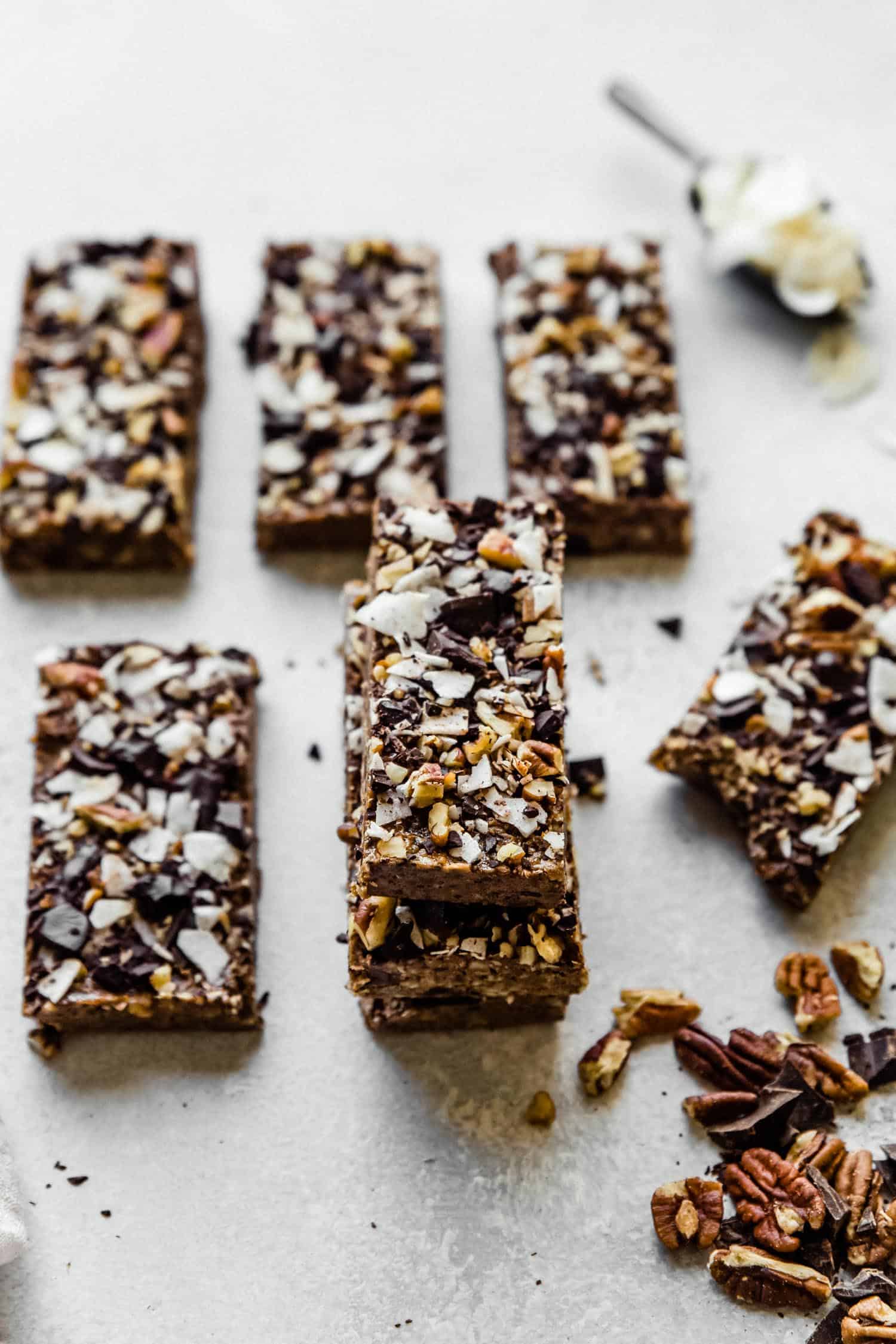 protein bars stacked in a pile with chocolate chips on top and coconut flakes