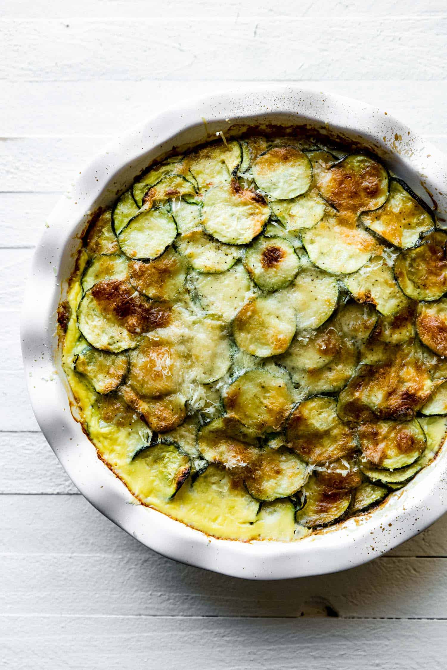 zucchini casserole in a pie plate with cheese on top