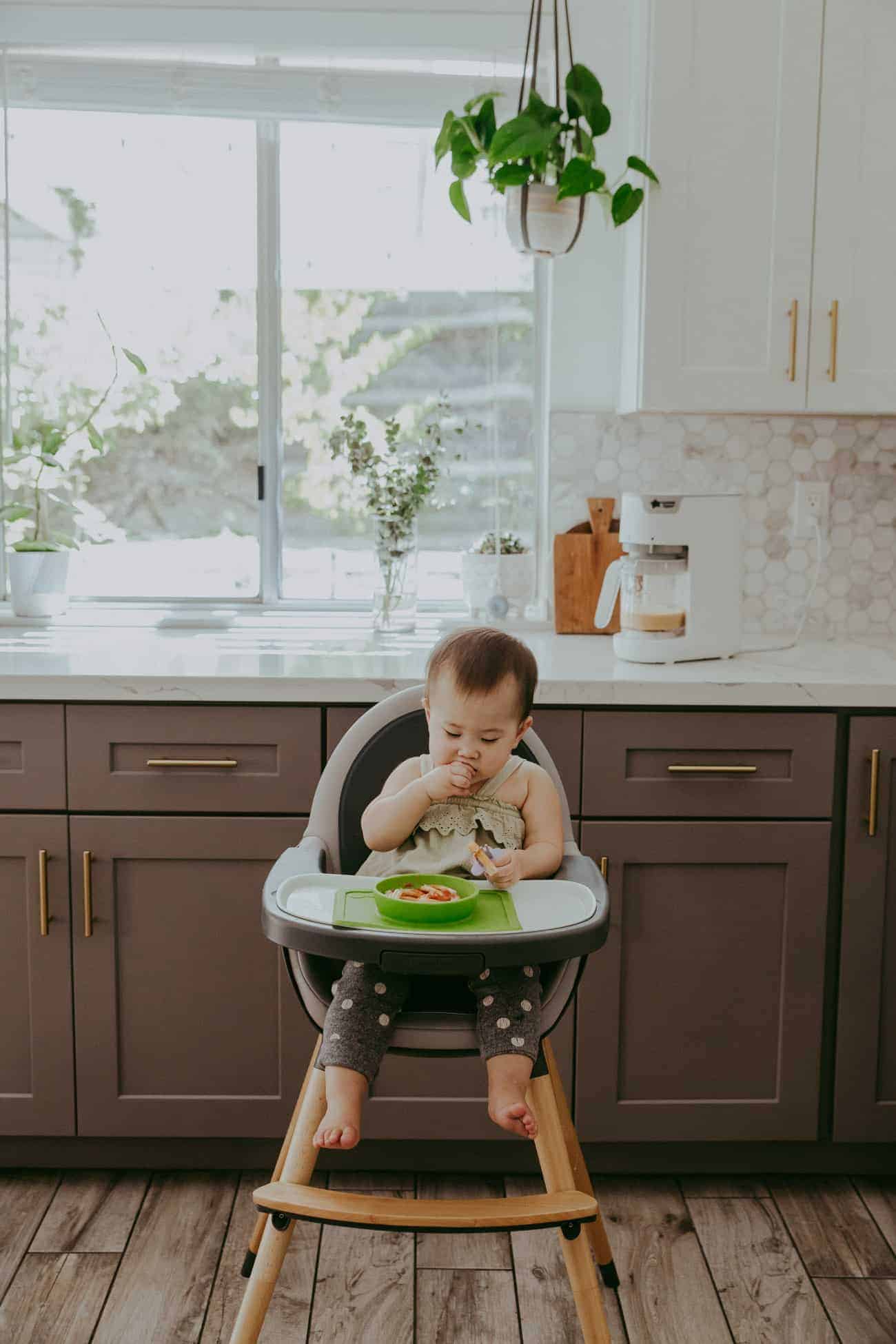 baby eating food in a gray and white high chair