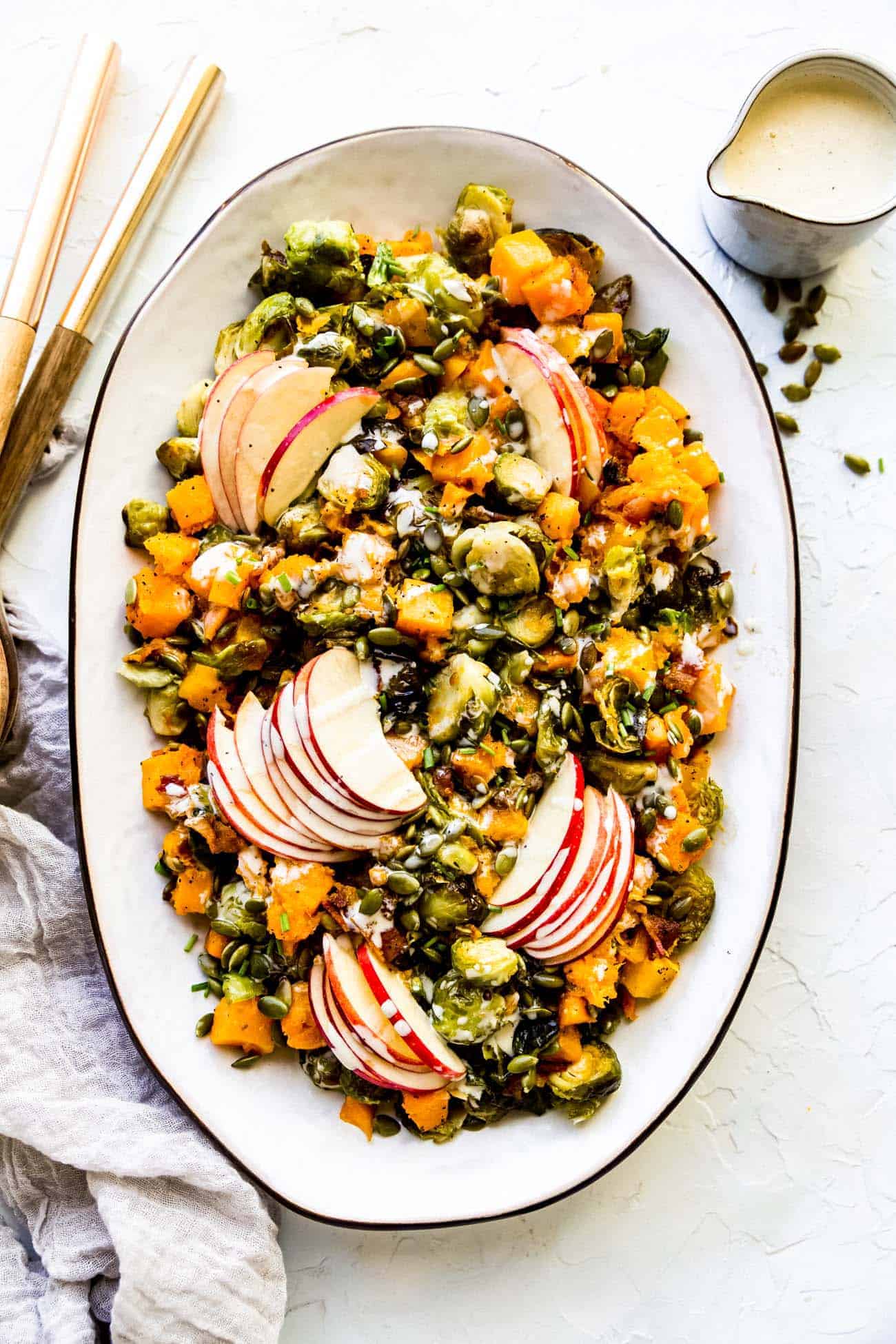 roasted butternut squash and brussels sprouts on a platter with apple and bacon