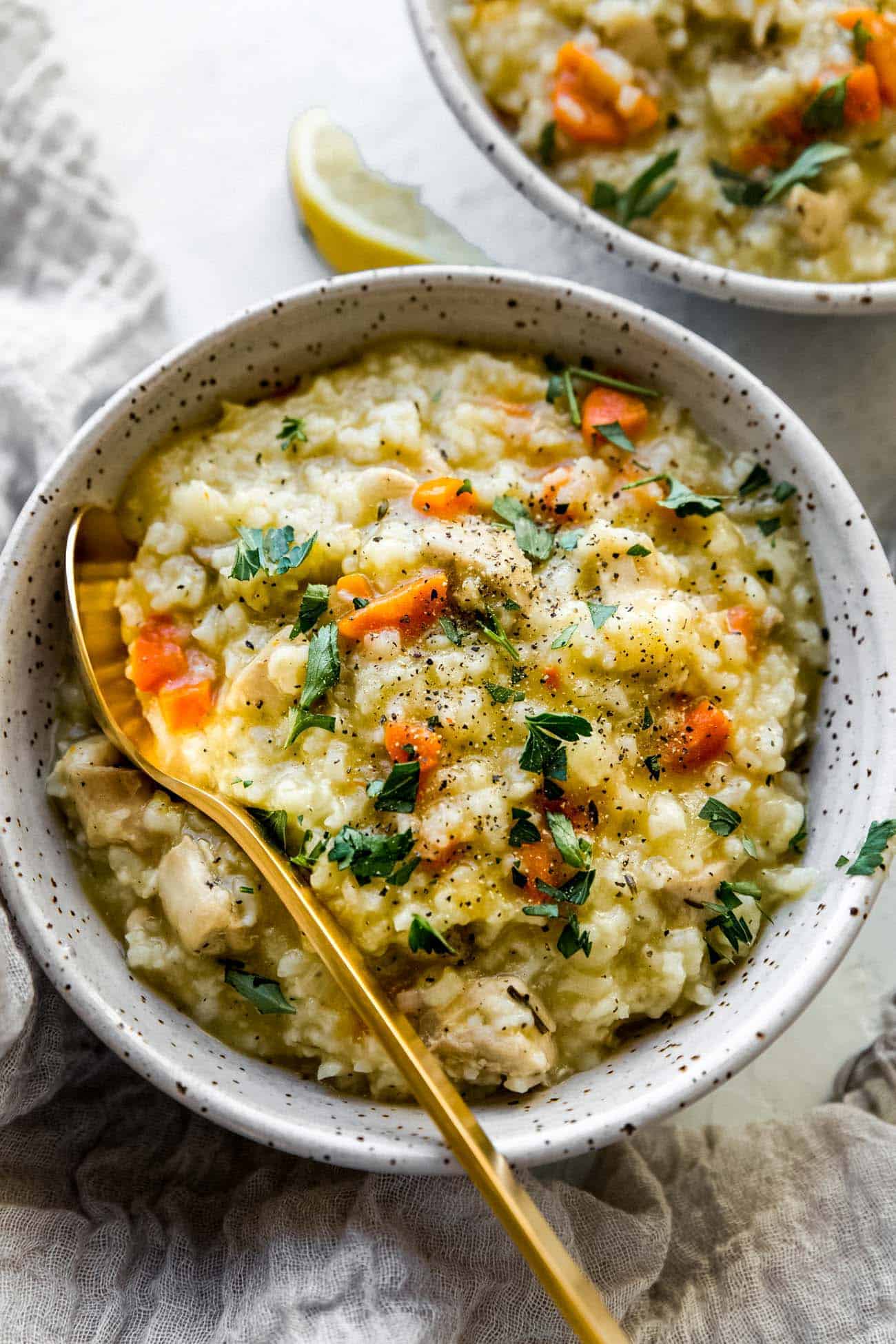 chicken and rice soup with fresh parsley on top and a gold spoon inside the bowl