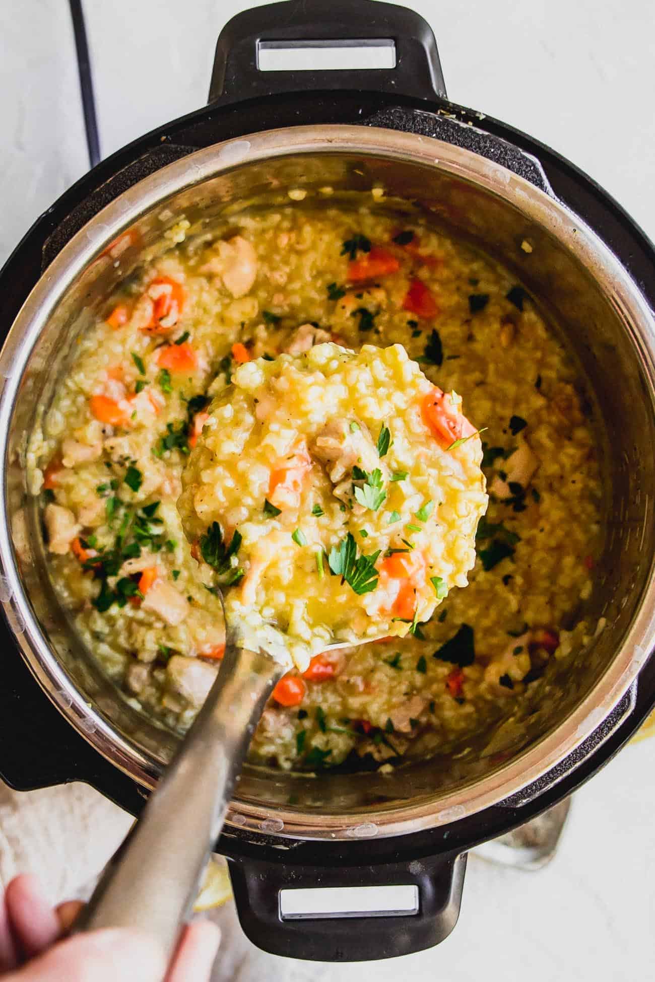 chicken and rice soup inside Instant Pot being served with a ladle