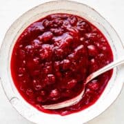 Instant Pot cranberry sauce in a white bowl with a spoon inside