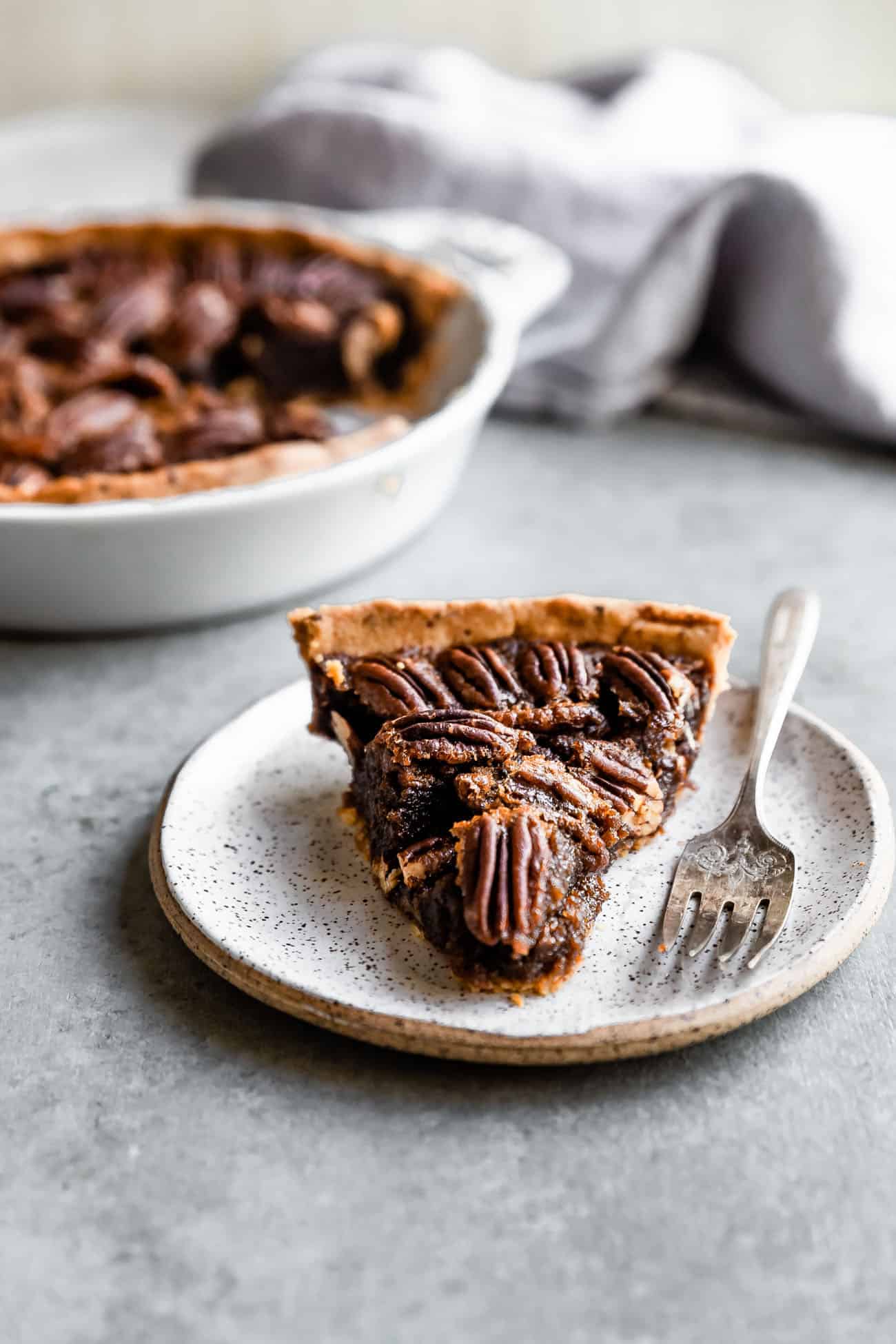 pecan pie on a white plate with a fork on the side