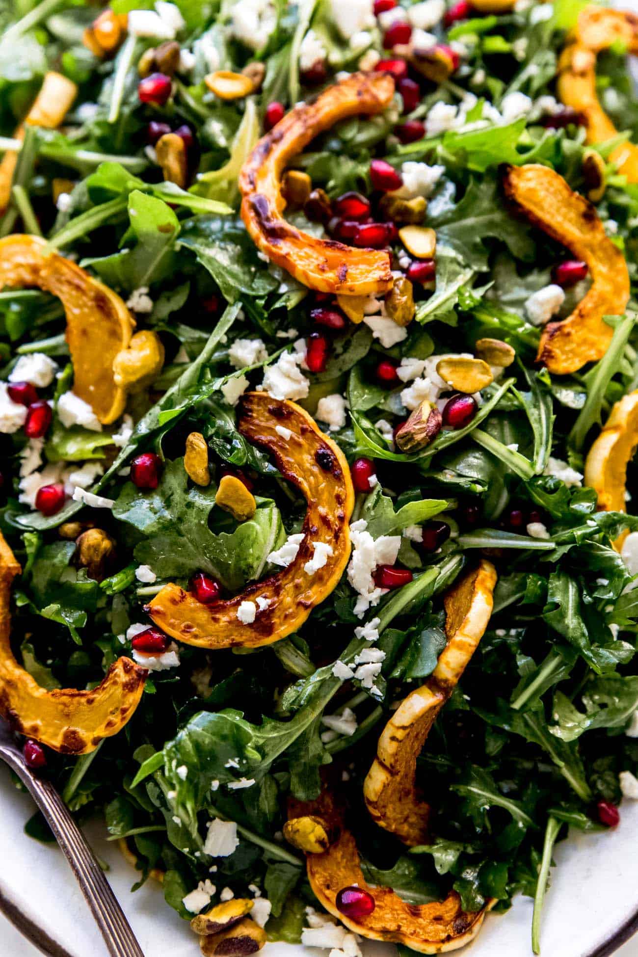 roasted delicata squash salad on a platter with pomegranates and feta cheese