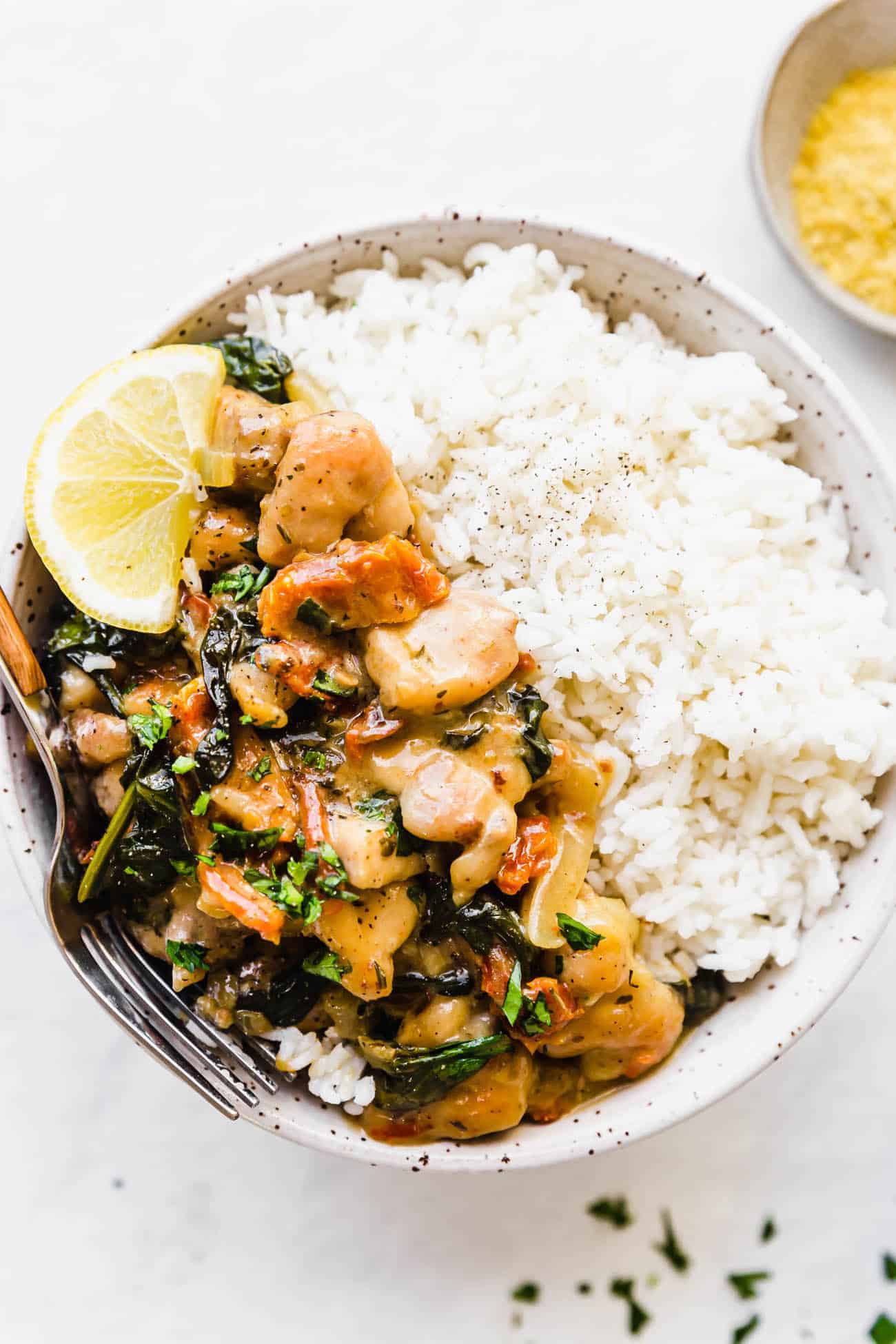 creamy garlic chicken with white rice in a bowl topped off with lemon