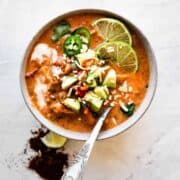 bowl of creamy taco soup with a spoon inside and avocado and limes on top