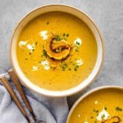 roasted delicata squash soup in a bowl with spoons on the side
