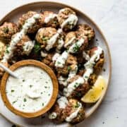 Lamb meatballs on a ceramic plate with tzatziki in a bowl