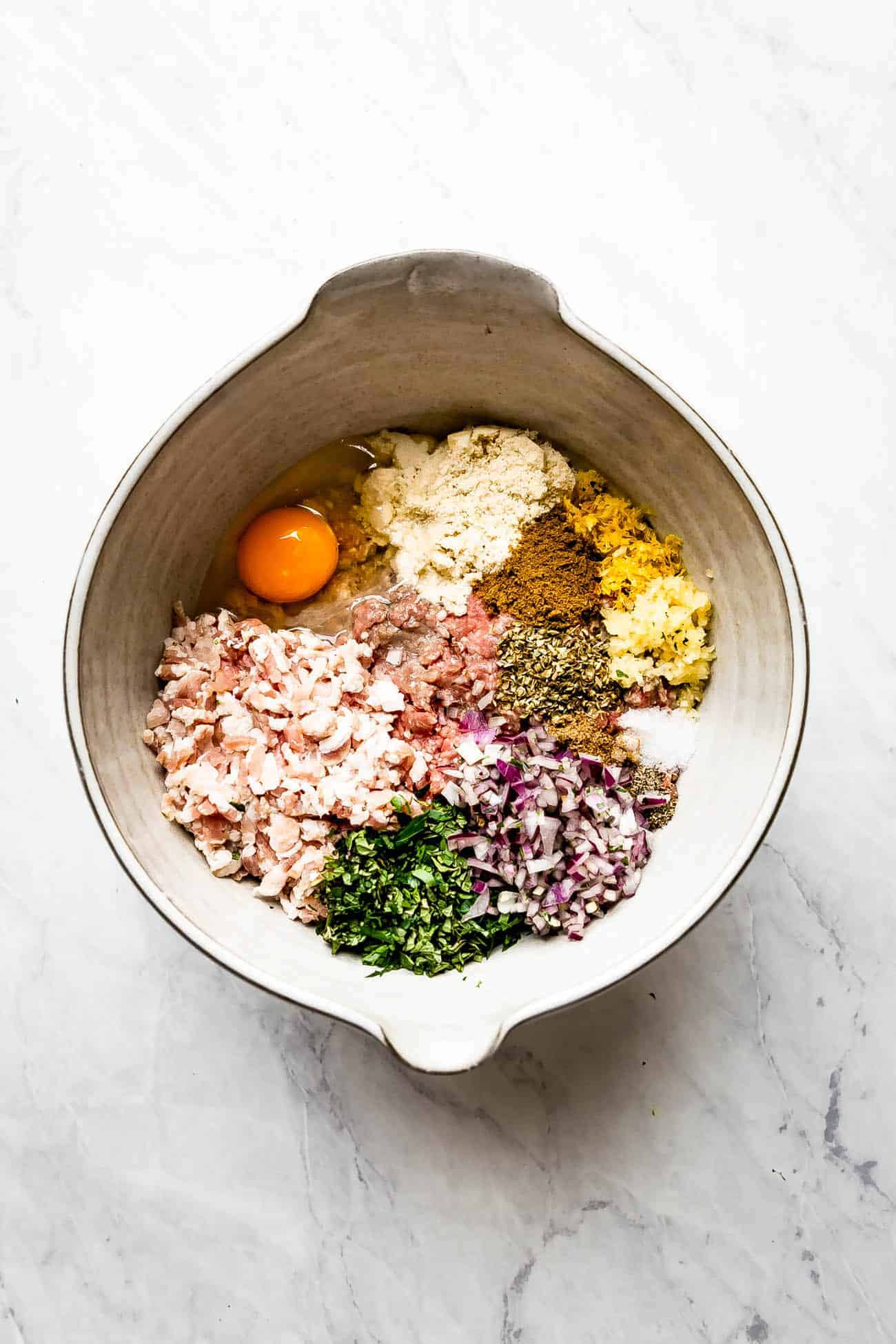 ingredients to make lamb meatballs in a large ceramic bowl