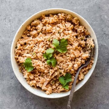 Spanish cauliflower rice in a white bowl with cilantro on top