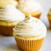 several vanilla cupcakes with vanilla buttercream frosting on top