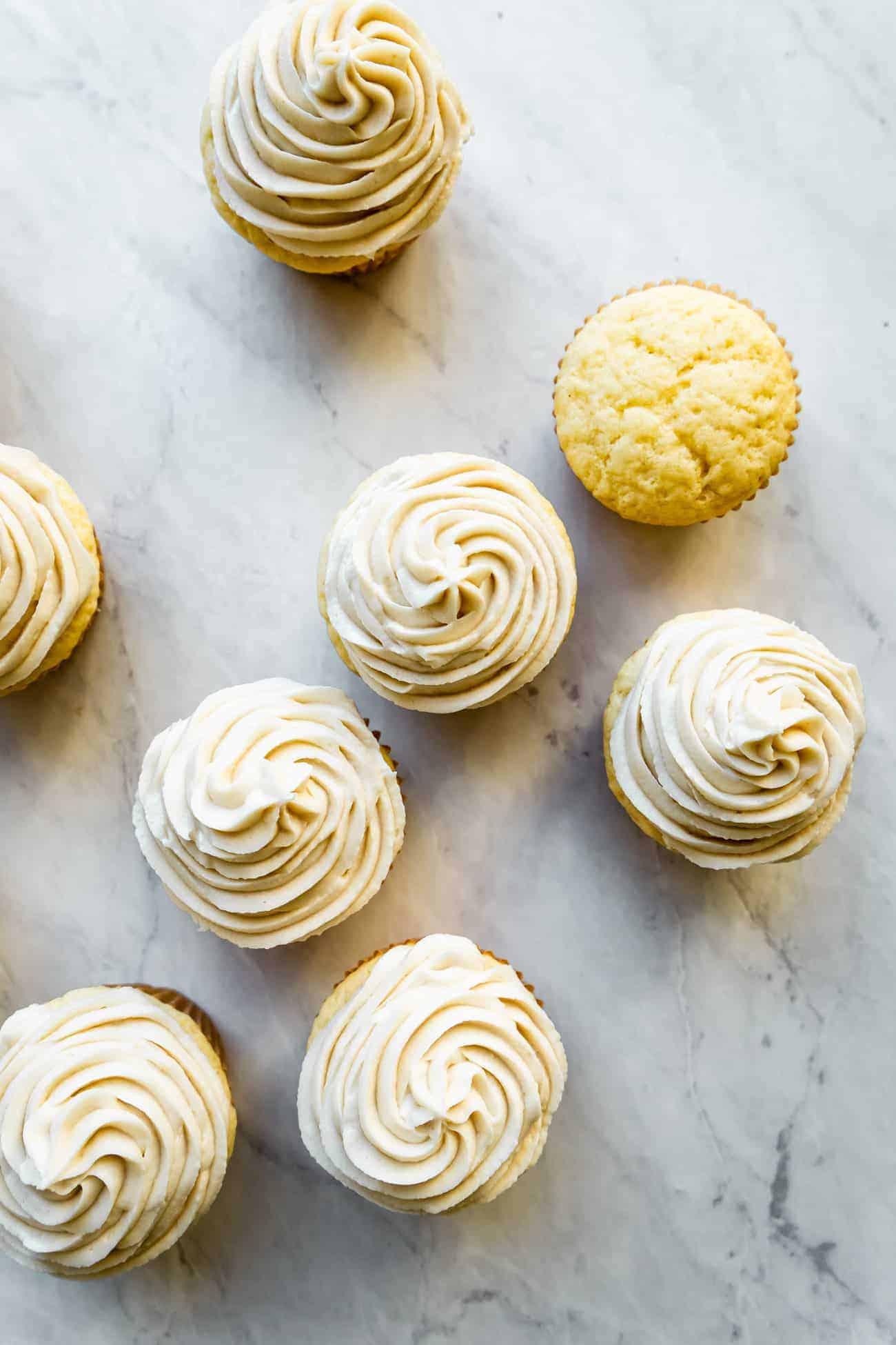 overhead of several vanilla cupcakes piped with keto buttercream frosting on top