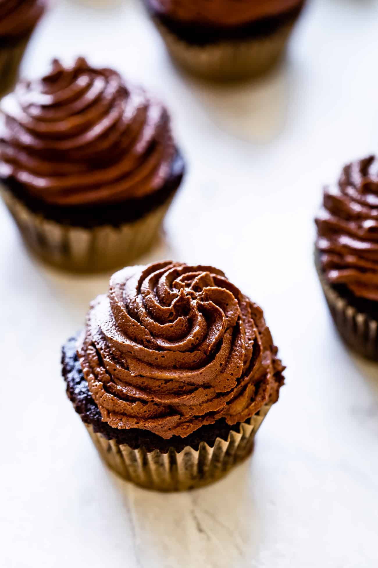 paleo chocolate buttercream frosted on chocolate cupcakes on a marble board
