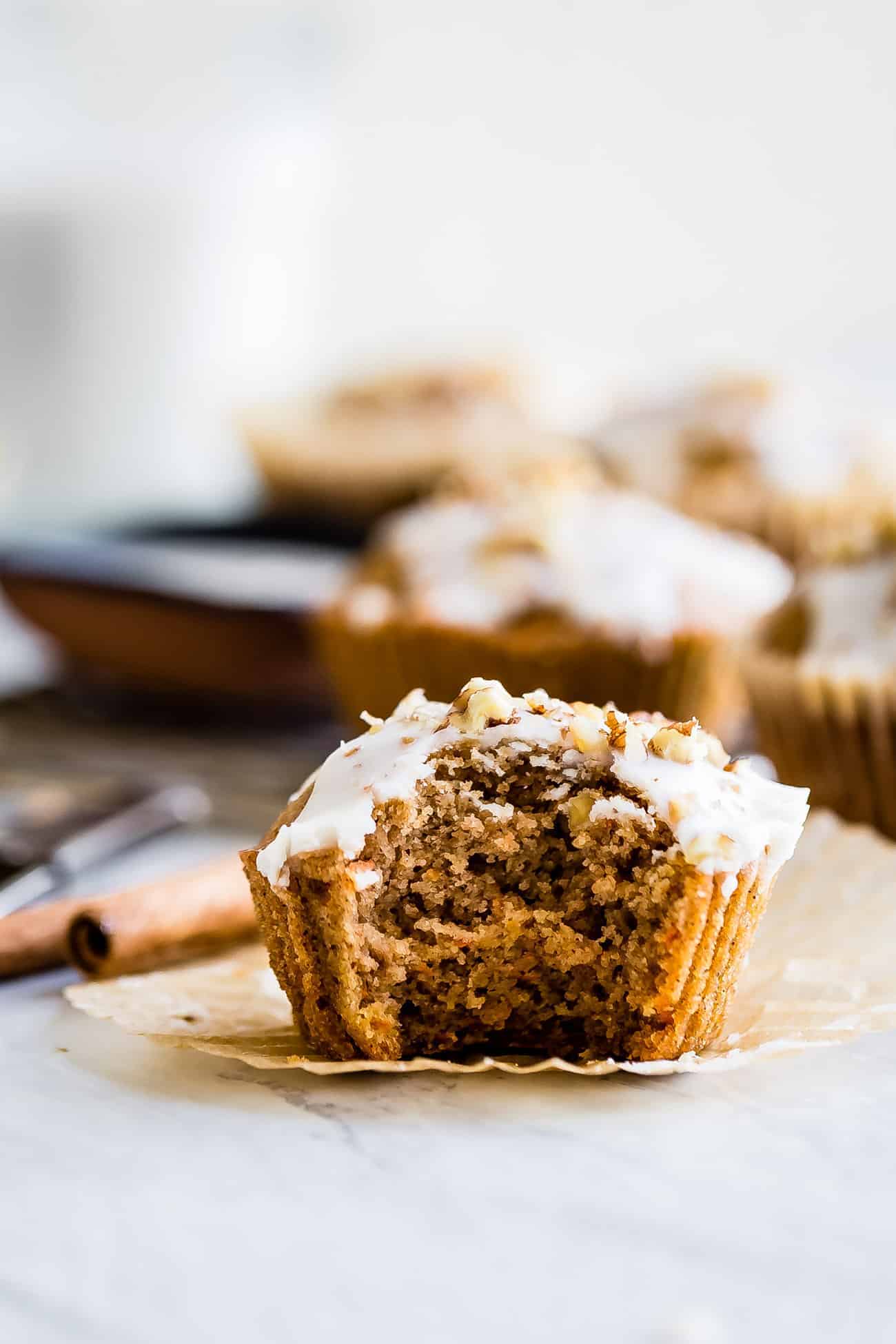 a healthy carrot cake muffin unwrapped with a bite taken out
