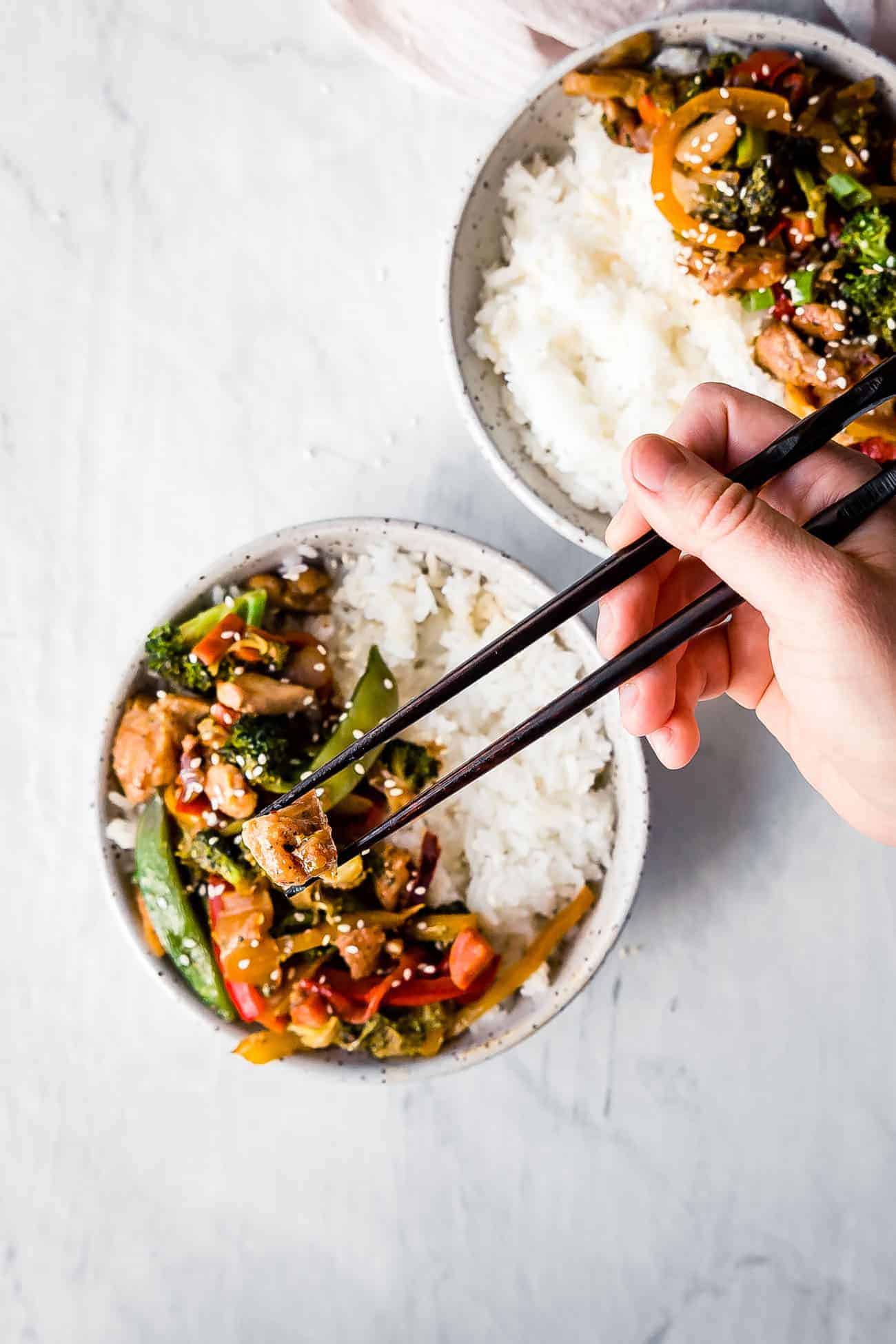 chopsticks grabbing keto chicken stir fry with rice from a bowl