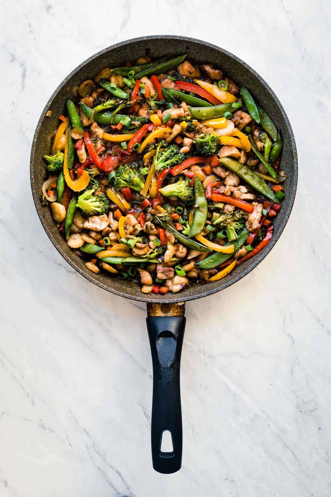 keto chicken stir fry in a frying pan with broccoli, peppers, and snap peas