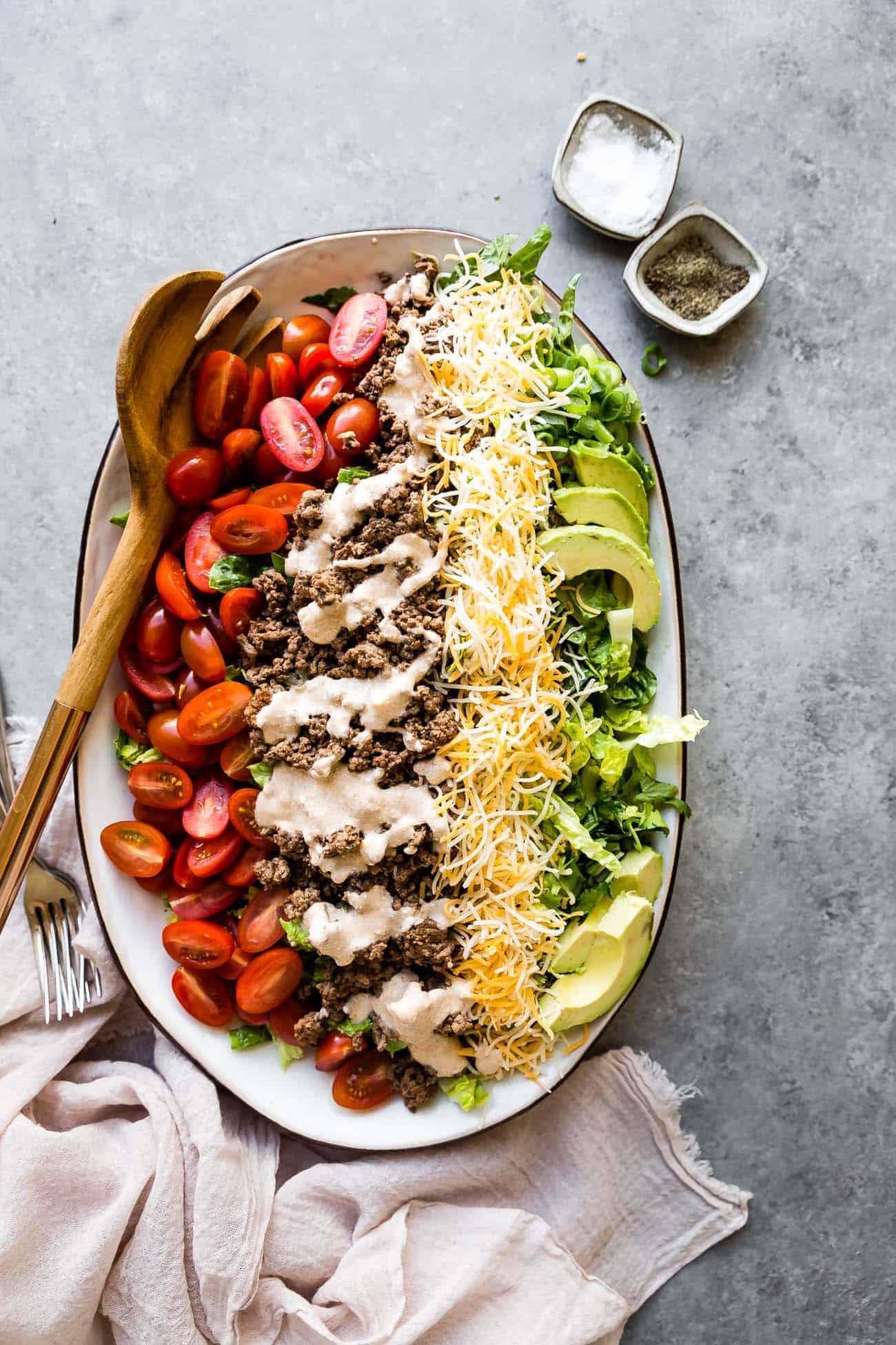 taco salad on a platter with tomatoes, shredded cheese, and avocado slices