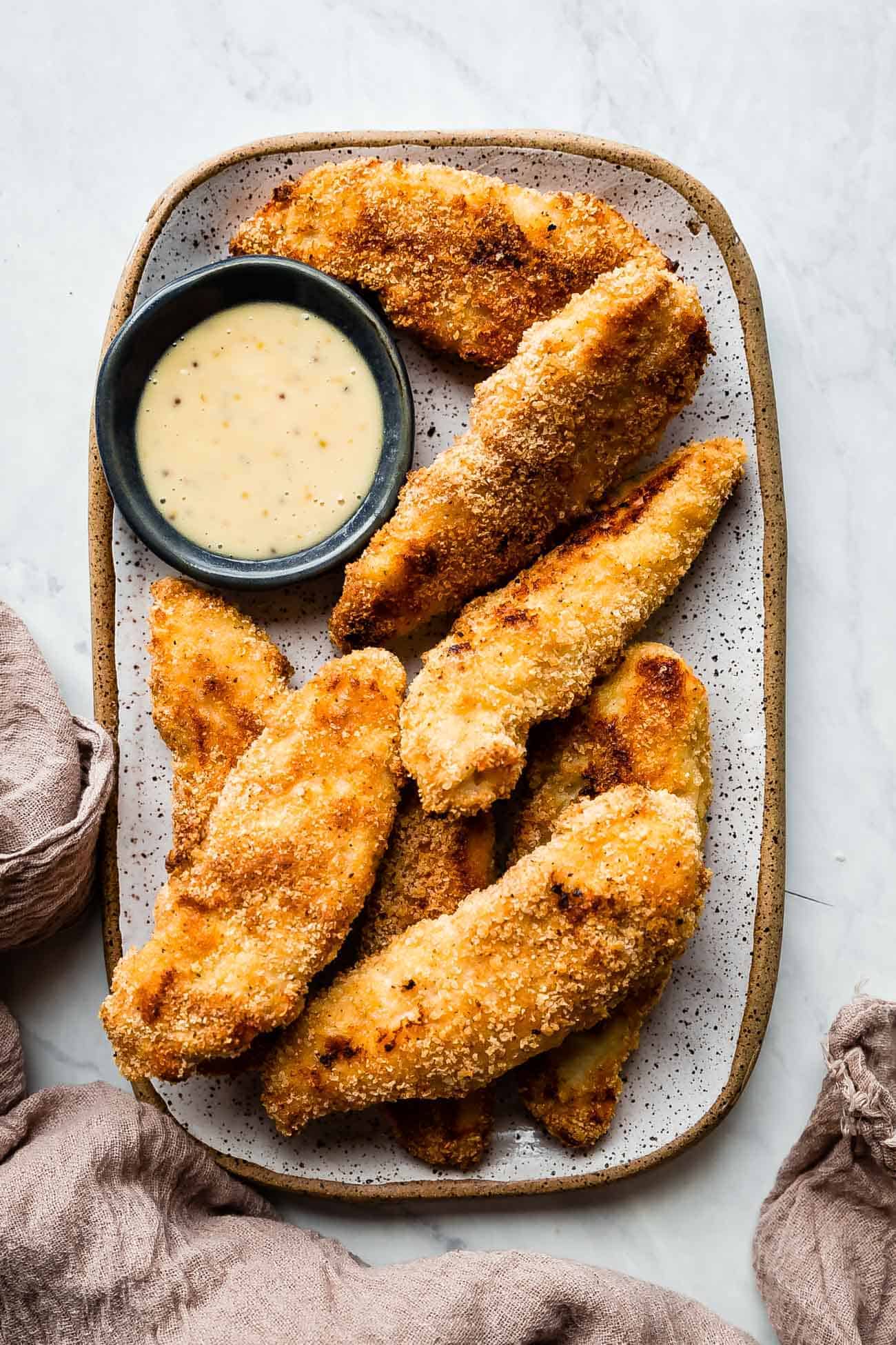 baked chicken strips on a tray with honey mustard sauce