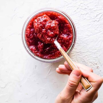 stirring strawberry chia jam in a glass jar