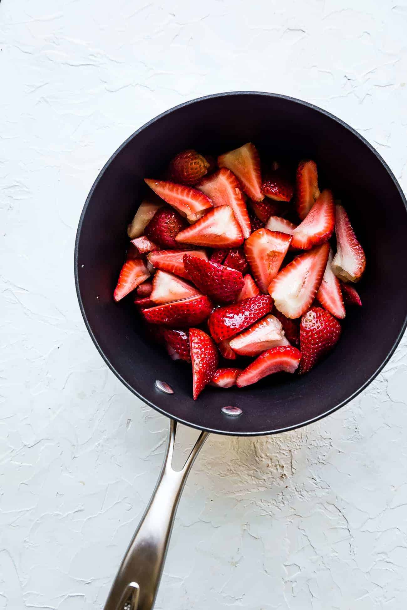 hulled and sliced strawberries in a saucepan
