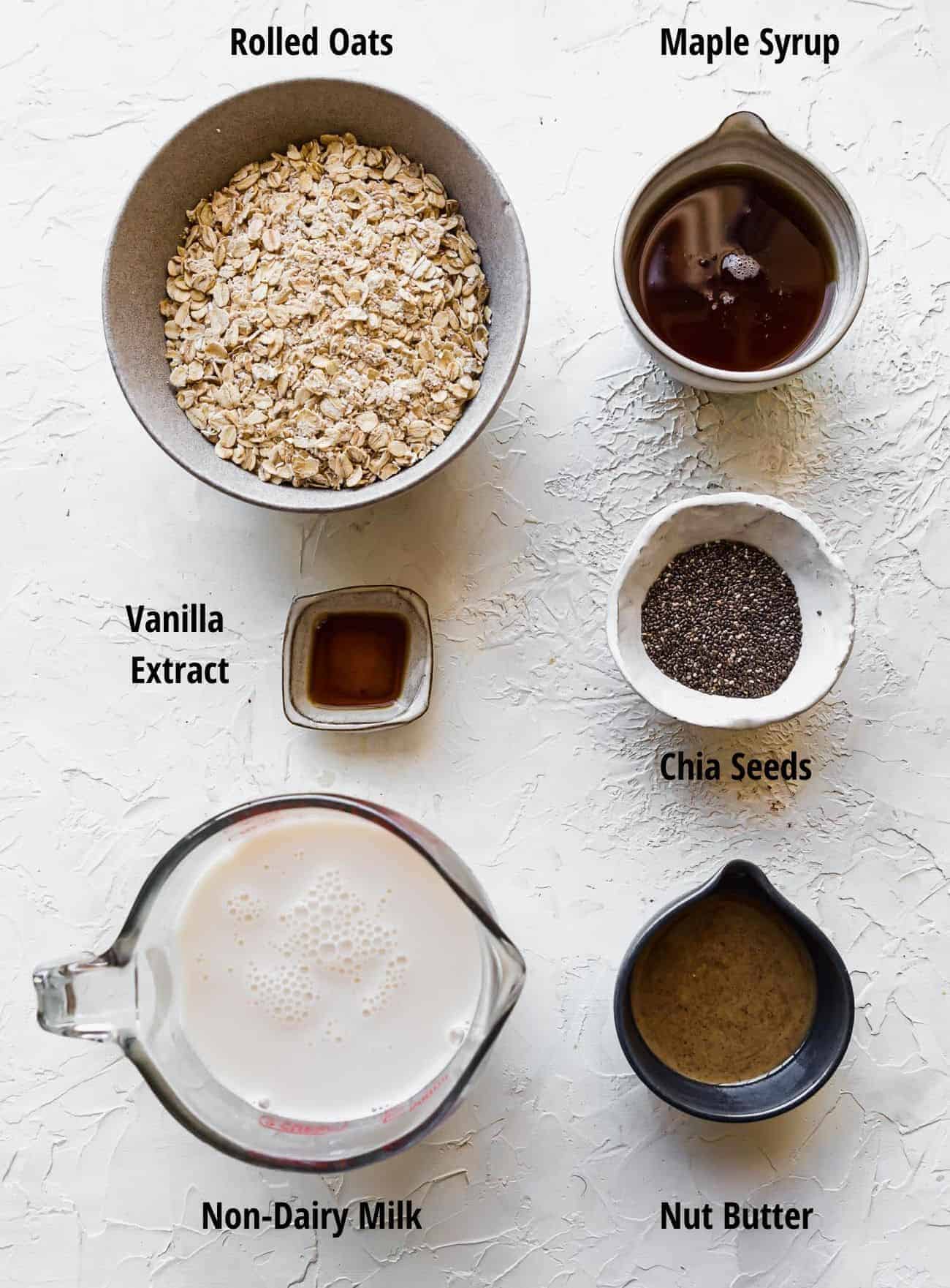 ingredients to make vegan overnight oats: rolled oats, maple syrup, chai seeds, vanilla extract, chia seeds, non-dairy milk, nut butter