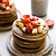 banana oatmeal pancakes on a plate with strawberries and bananas on top