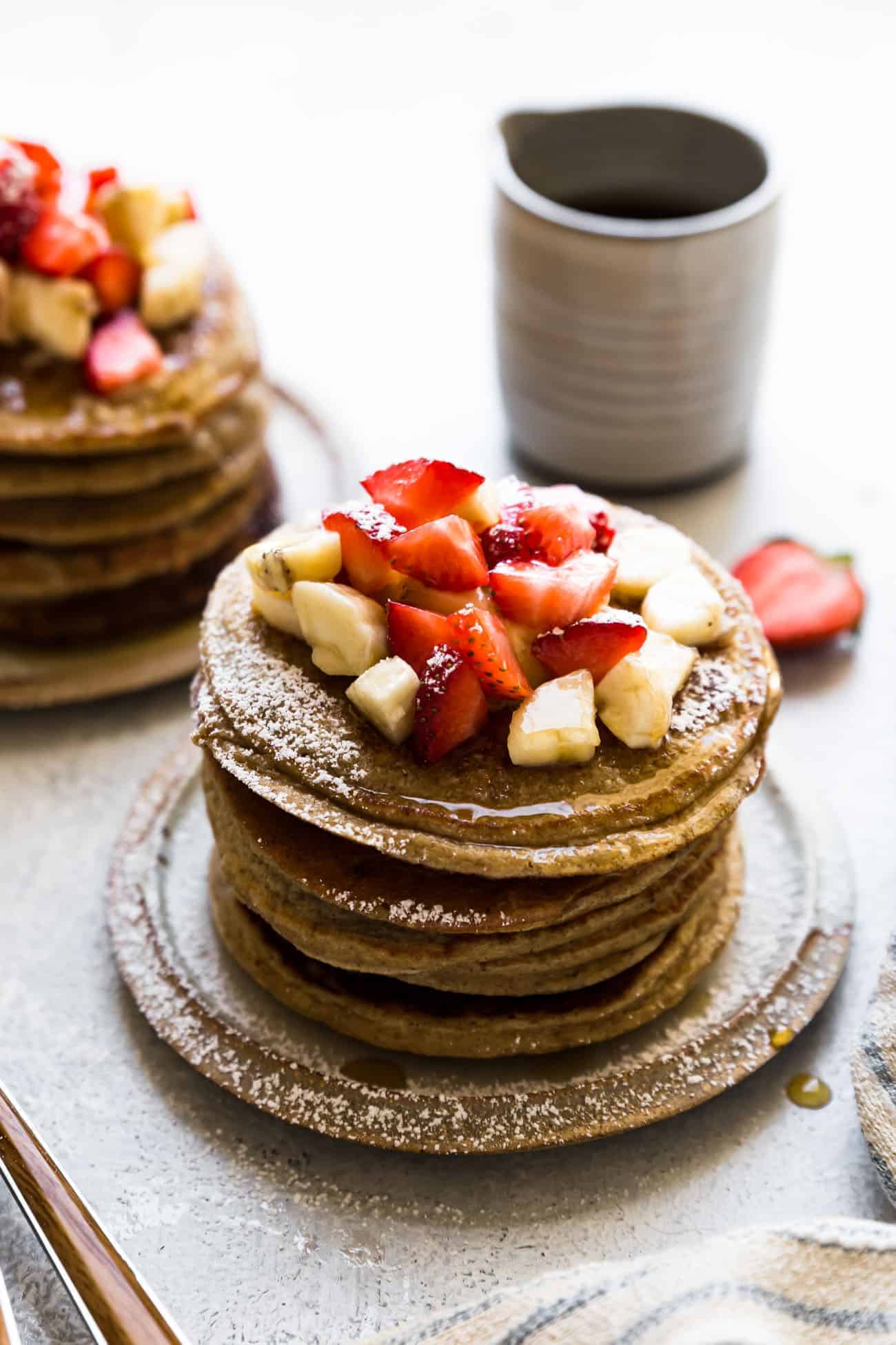 banana oatmeal pancakes on a plate with strawberries and bananas on top