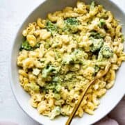 vegan mac and cheese made with cashew cheese in a bowl with a gold fork and brocoli