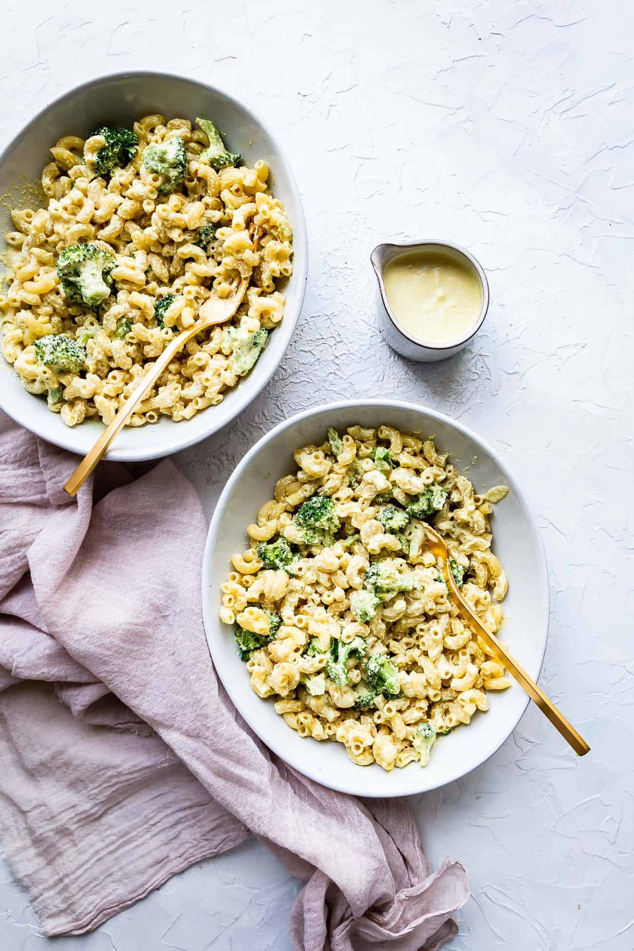 two bowls of mac and cashew cheese with broccoli 