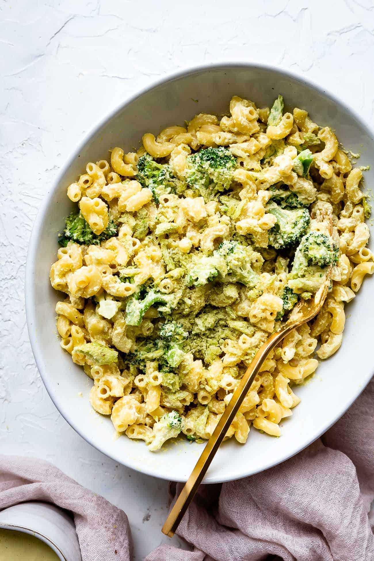 vegan mac and cheese made with cashew cheese in a bowl with a gold fork and brocoli