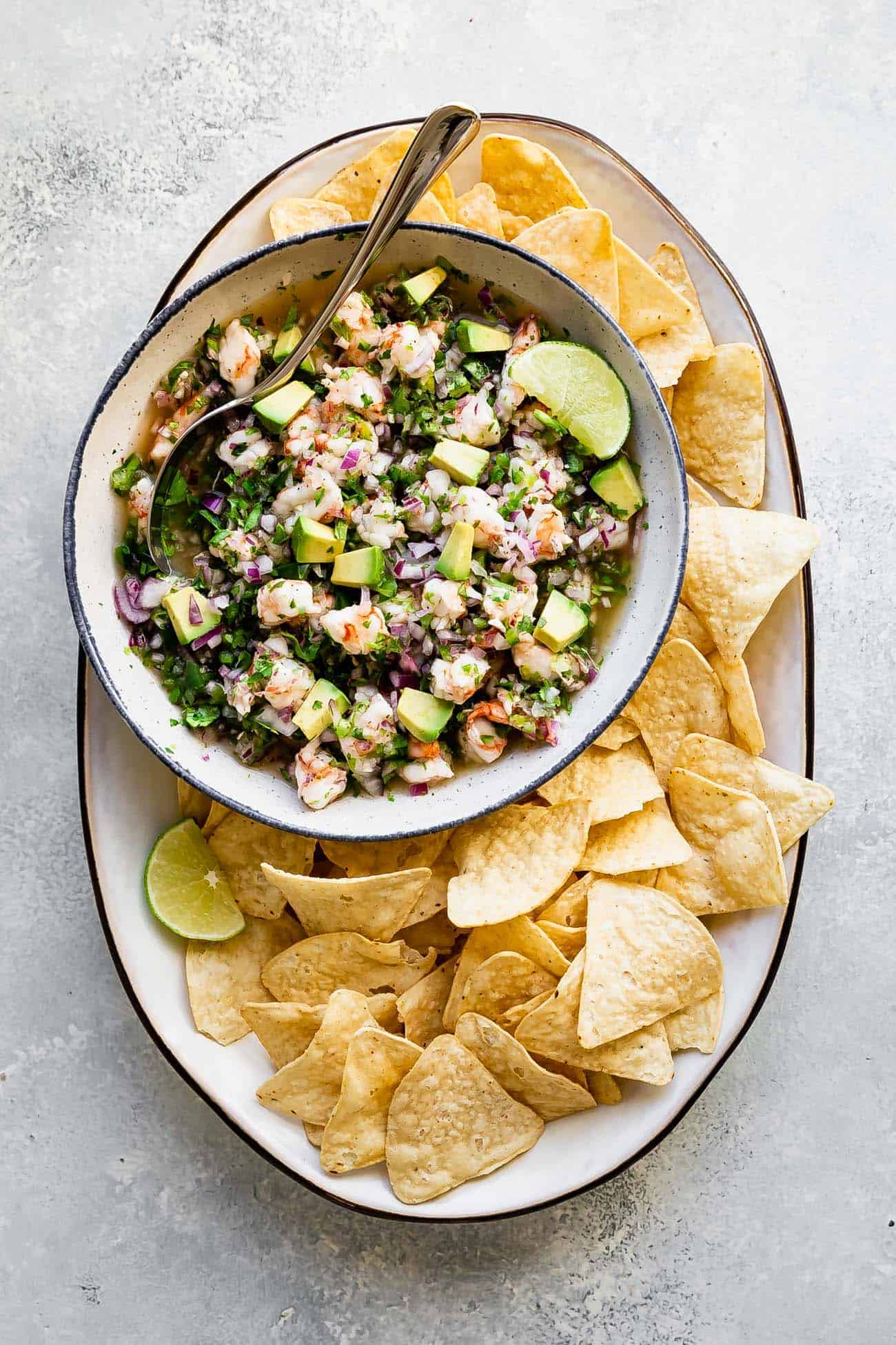 tortilla chips on a platter with shrimp ceviche in a bowl