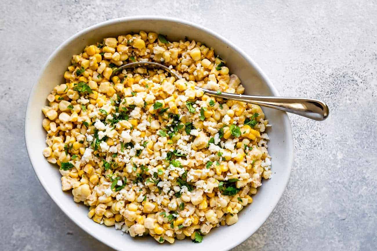 healthy elote dip in a bowl with cilantro and cotija cheese on top