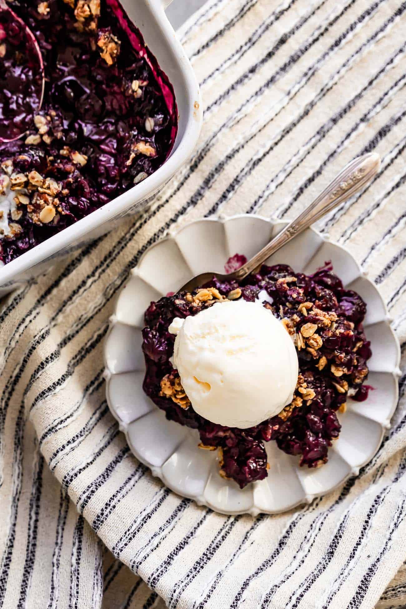 blueberry crisp on a plate with a scoop of vanilla ice cream