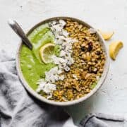 green smoothie in a bowl with granola and lemon toppings