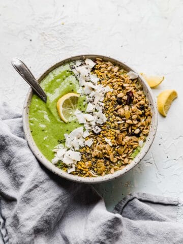 green smoothie in a bowl with granola and lemon toppings